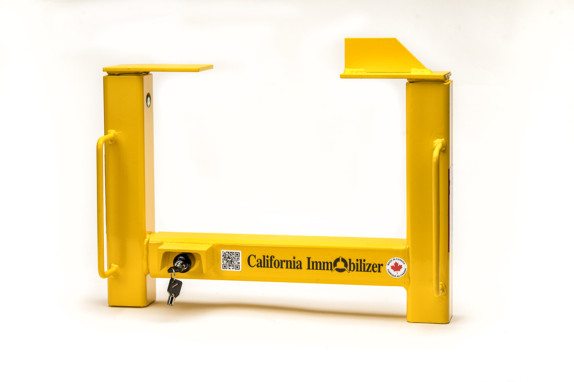 Bright yellow California Immobilizer trailer wheel lock securing a utility trailer tire.
